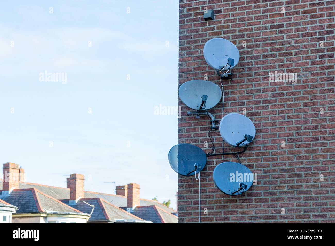Un gruppo di piatti satellite sul lato di un edificio in mattoni Foto Stock