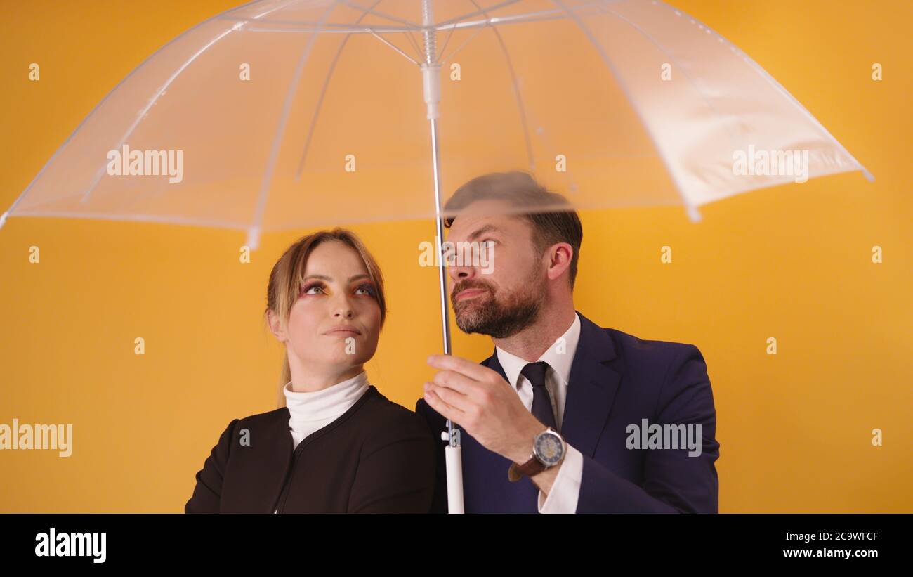 Colleghi di affari , uomo e donna che riparano sotto un ombrello trasparente. Foto di alta qualità Foto Stock
