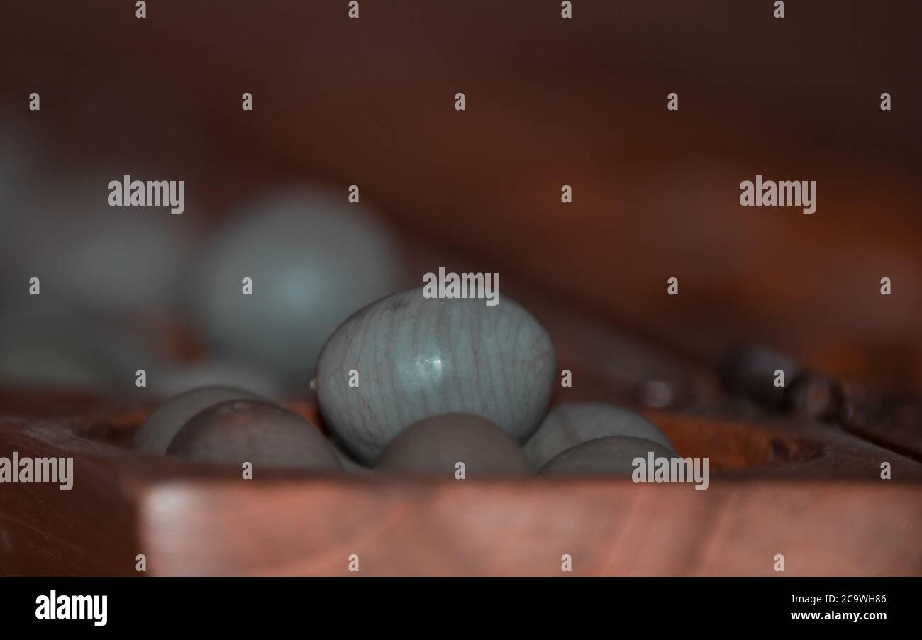 Primo piano di un gioco di mancala in legno con pietre grigie Foto Stock