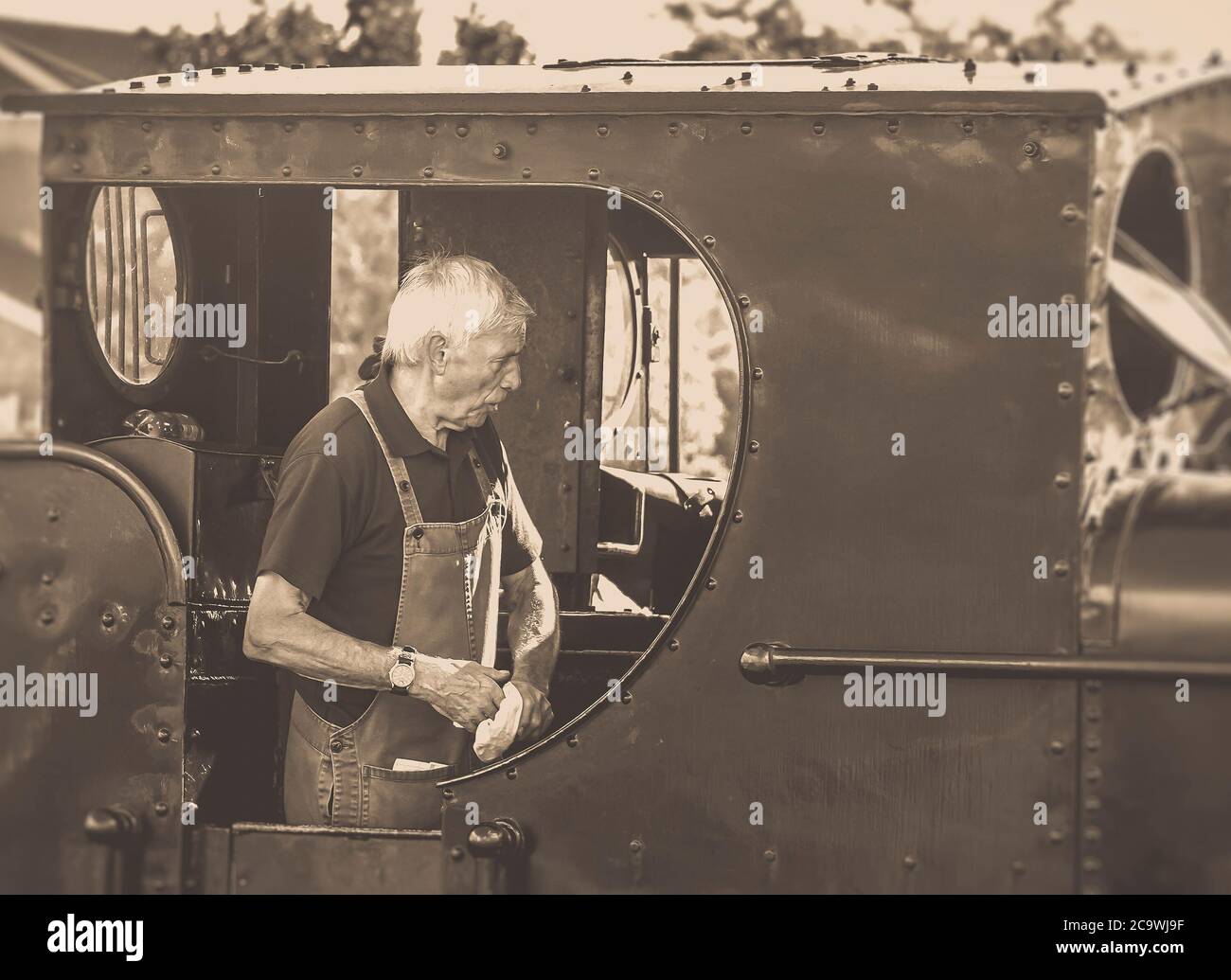 Primo piano autista del treno a vapore in un taxi vintage della locomotiva a vapore del Regno Unito che si prepara alla partenza alla stazione ferroviaria Heritage. Equipaggio ferroviario a vapore. Foto Stock
