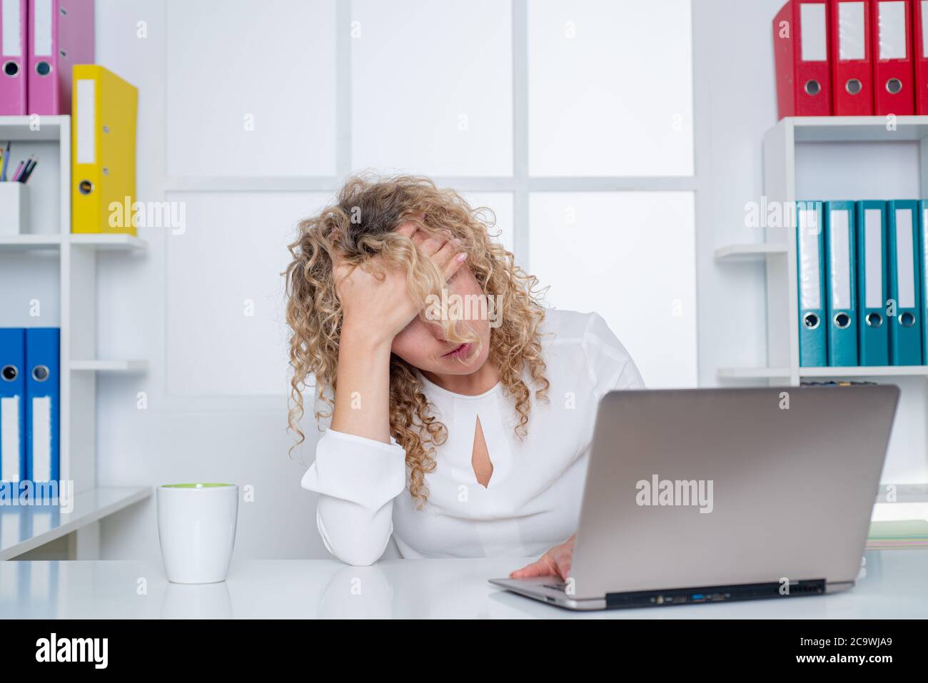 Stanco lavoratore d'ufficio. Donna pigra annoiata che usa il computer portatile la mattina, noiosa in ufficio. Foto Stock