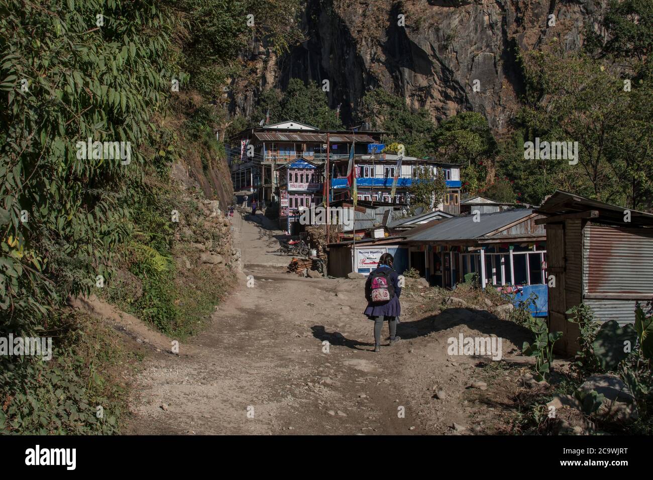 Giovane ragazza che cammina in un piccolo villaggio di montagna, circuito di Annapurna, Nepal Foto Stock