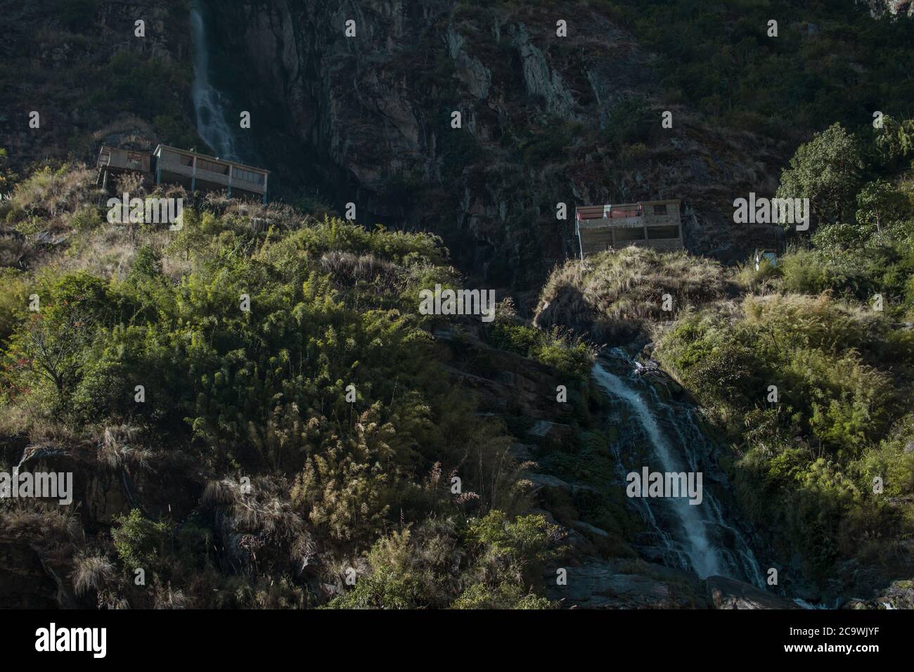 Cascata che scorre tra due case da tè, nel fiume Marshyangdi, circuito Annapurna, Nepal Foto Stock