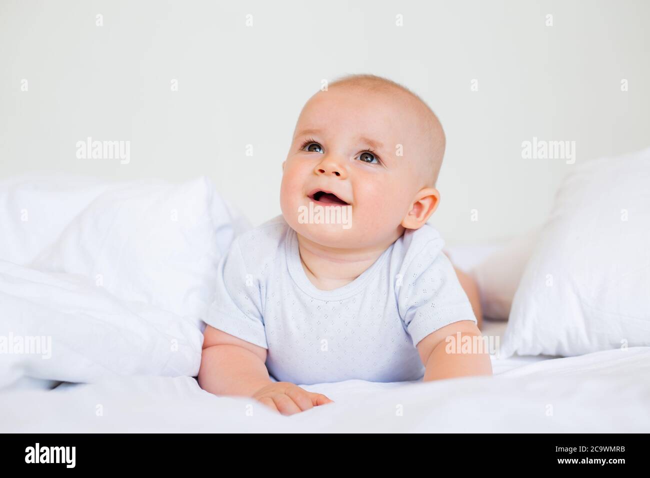 Carino bambino ragazzo sorridente si trova nel letto della casa. Biancheria da letto per i bambini Foto Stock