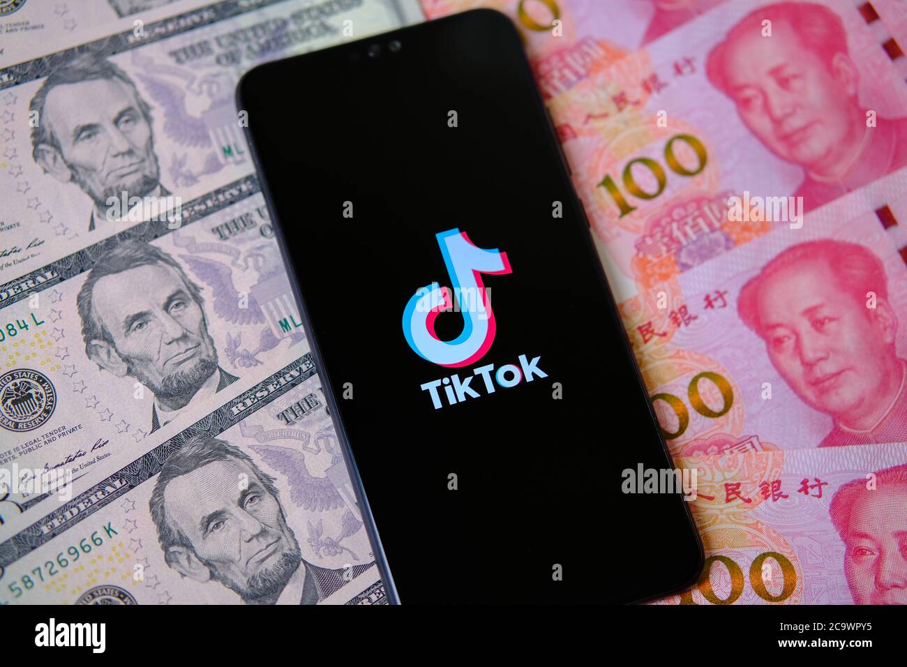 TikTok app logo sullo schermo e dollari con yuan soldi circa Foto Stock