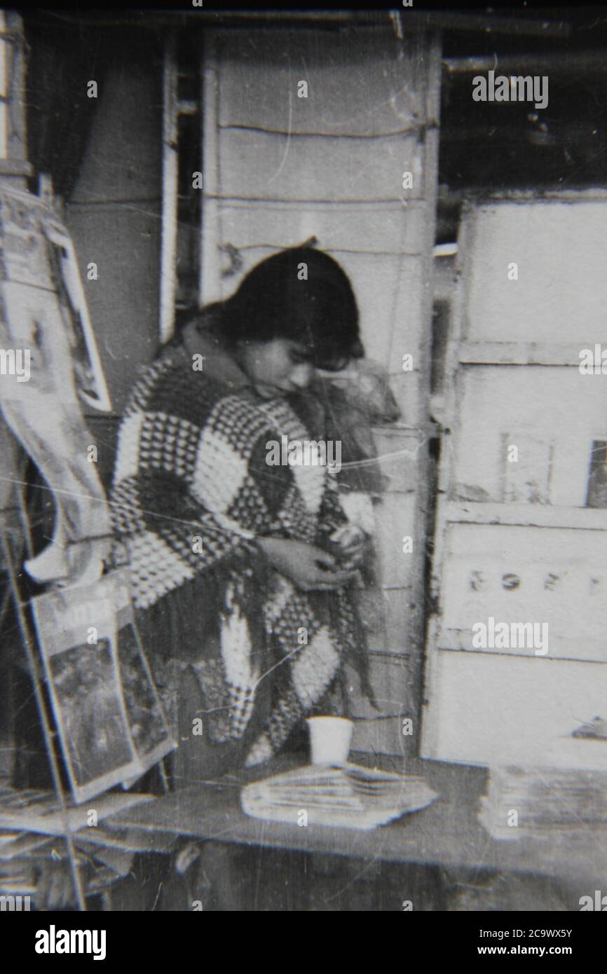 Fine anni '70 vintage nero e bianco stile di vita fotografia di una povera ragazza che pregava per soldi. Foto Stock