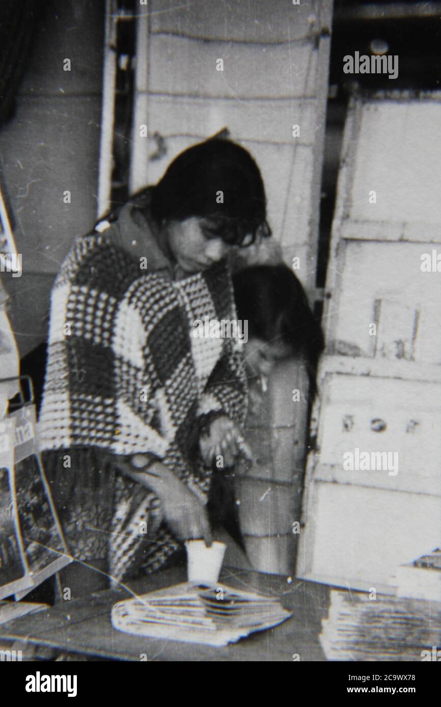Fine anni '70 vintage nero e bianco stile di vita fotografia di una povera ragazza che pregava per soldi. Foto Stock