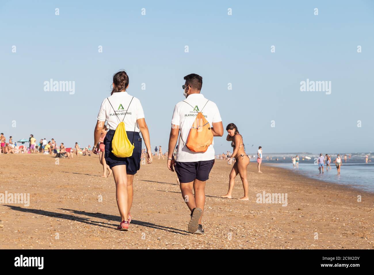 Punta Umbria, Huelva, Spagna - 2 agosto 2020: Guardia di sicurezza della spiaggia di Junta de Andalucia sta controllando l'allontanamento sociale e l'uso della maschera protettiva Foto Stock