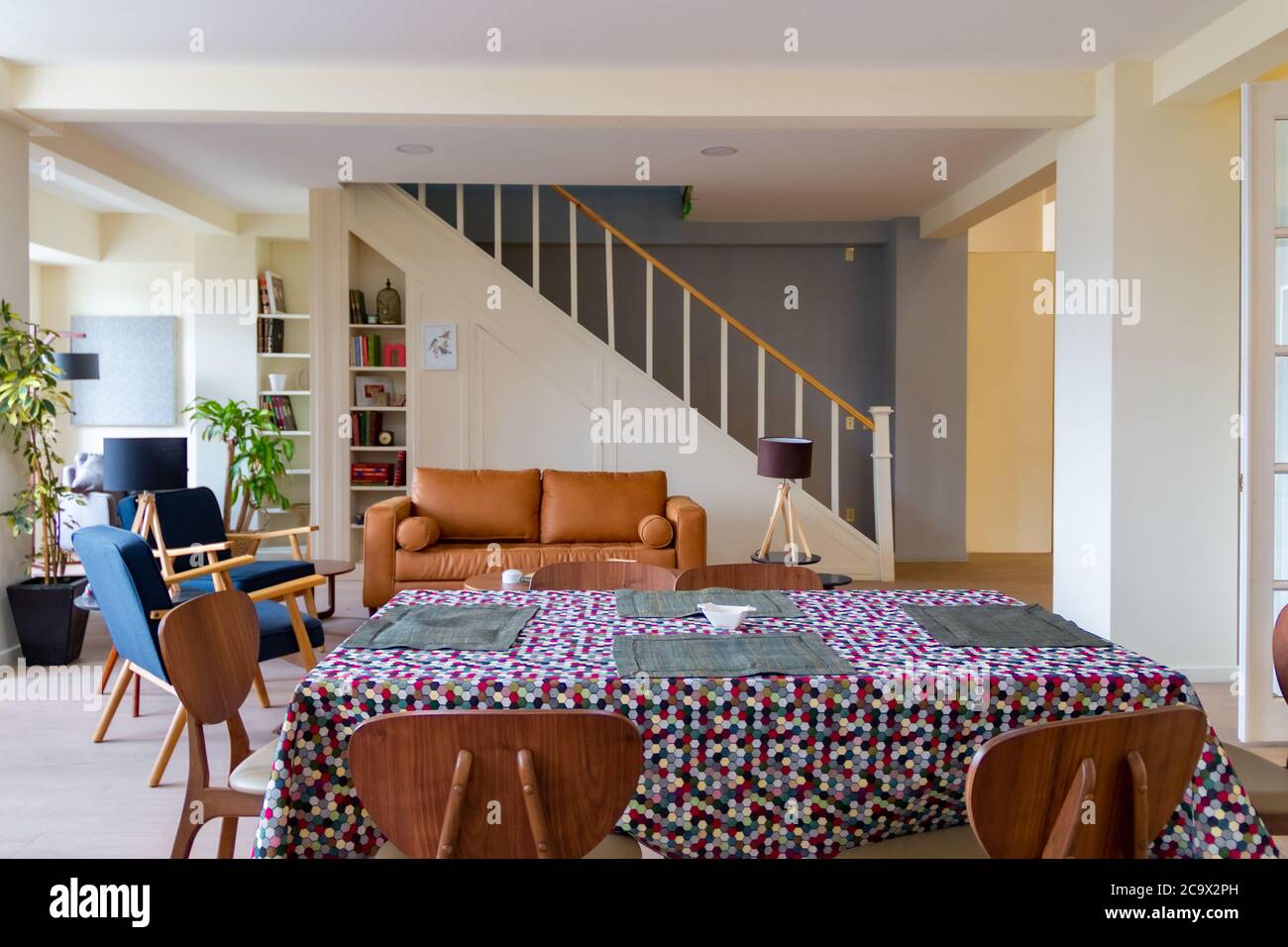 Camera moderna con poltrona marrone e scale sullo sfondo. Sala da pranzo fiorita Foto Stock