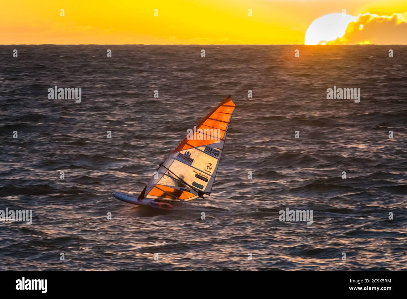 Tramonto d'oro sulla splendida spiaggia di Brighton ad Adelaide, Australia del Sud, mentre il suo windsurf si muove retroilluminato attraverso l'oceano meridionale. Foto Stock