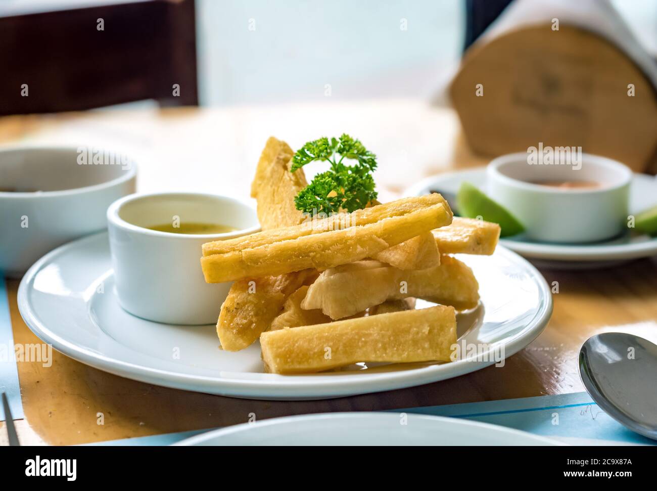 Manioca fritta (yuca frita) servita come contorno con coriandolo e diverse salse in un ristorante di Lima, Perù Foto Stock