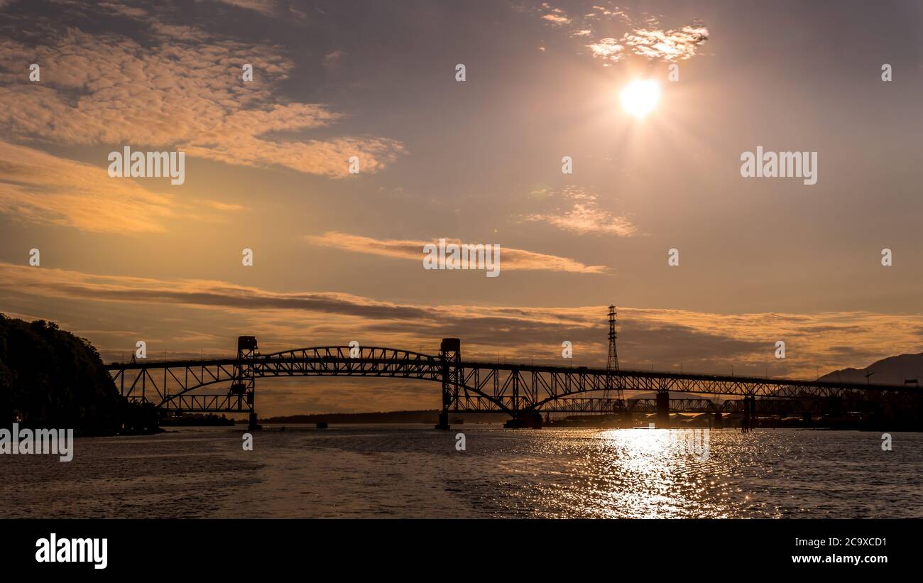 Tramonto sul secondo ponte Narrows (Ironworkers Bridge) della Trans Canada Highway e un ponte ferroviario, sopra Burrard Inlet e Vancouver Harbour Foto Stock