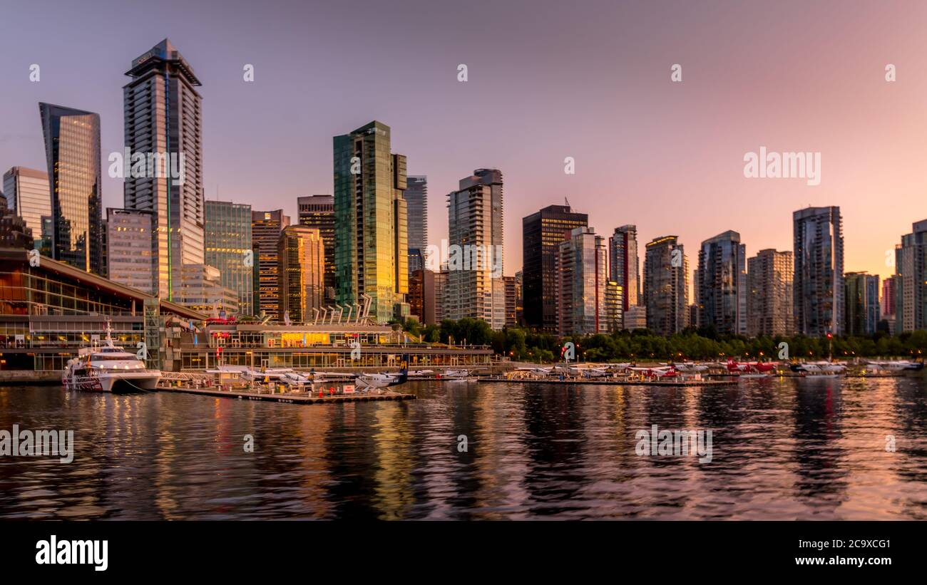 Tramonto sugli alti edifici e terminal degli aerei galleggianti lungo la riva del Coal Harbour nel centro di Vancouver Foto Stock