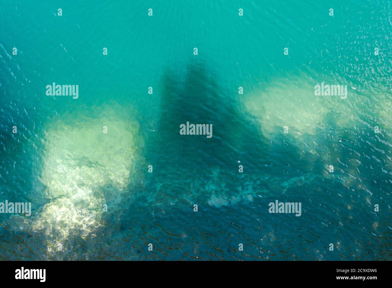 vista aerea dall'alto della superficie dell'acqua turchese con alberi all'ombra vicino alla riva del lago di cava Foto Stock