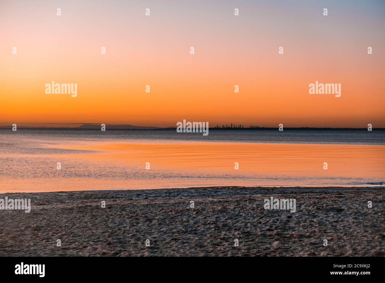 Grattacieli della città lontani al tramonto sulla spiaggia dell'oceano - paesaggio minimalista con spazio per le copie Foto Stock