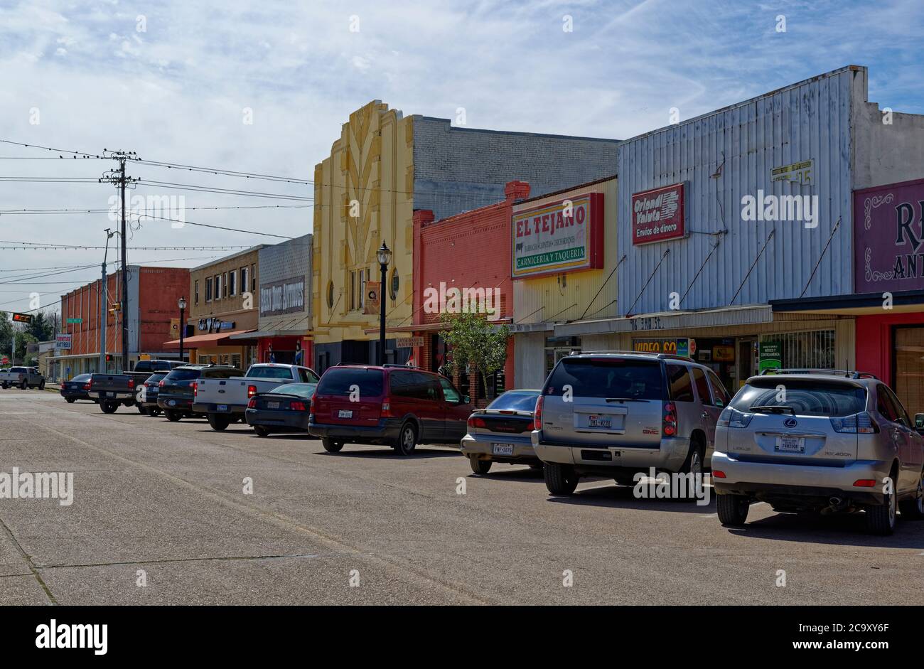 Auto parcheggiate, camion e SUVÕs di fronte a negozi e negozi, dipinte in vari colori su una strada a Rosenberg in Texas. Foto Stock