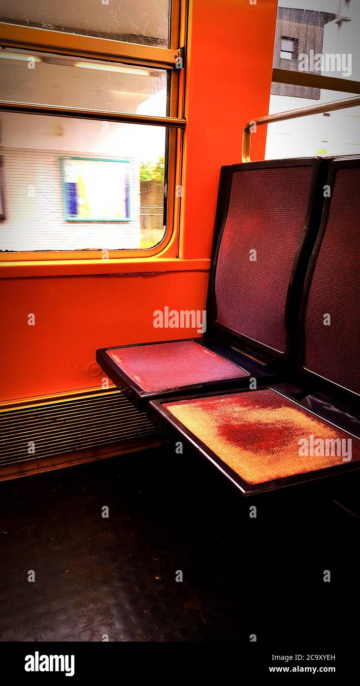 Interno arancione luminoso di un treno che mostra posti vuoti e la luce del sole che filtra attraverso la finestra a mezzogiorno Foto Stock