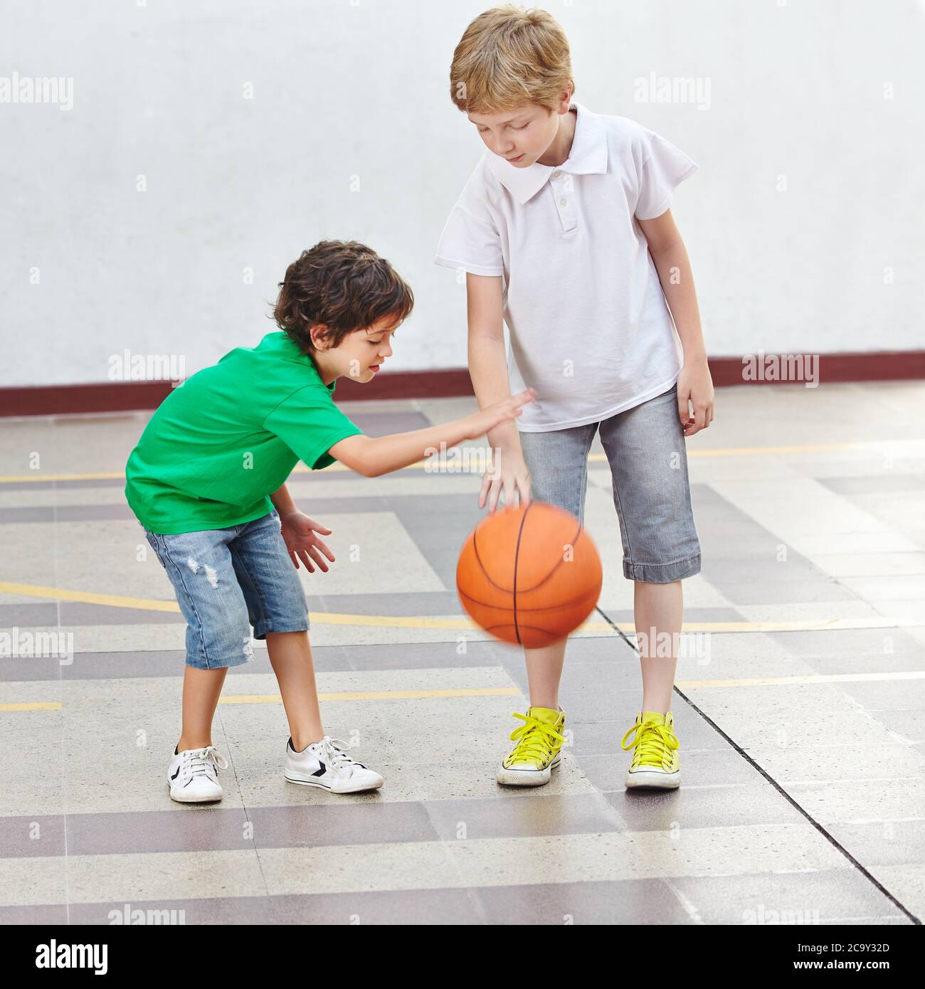Due bambini giocano a basket insieme nel parco giochi della scuola Foto Stock