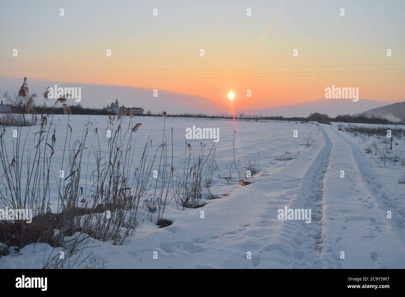 Paesaggio del tramonto invernale con le stampe degli pneumatici nella neve. Foto Stock