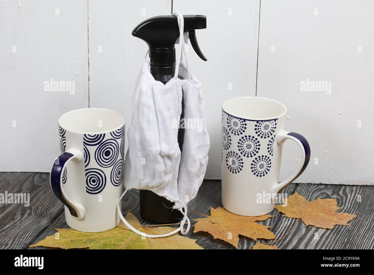 Due tazze in ceramica. Tra di loro ci sono maschere protettive per tutta la durata della pandemia. Appendere un flacone spray con un antisettico. Prima che loro siano asciugati Foto Stock