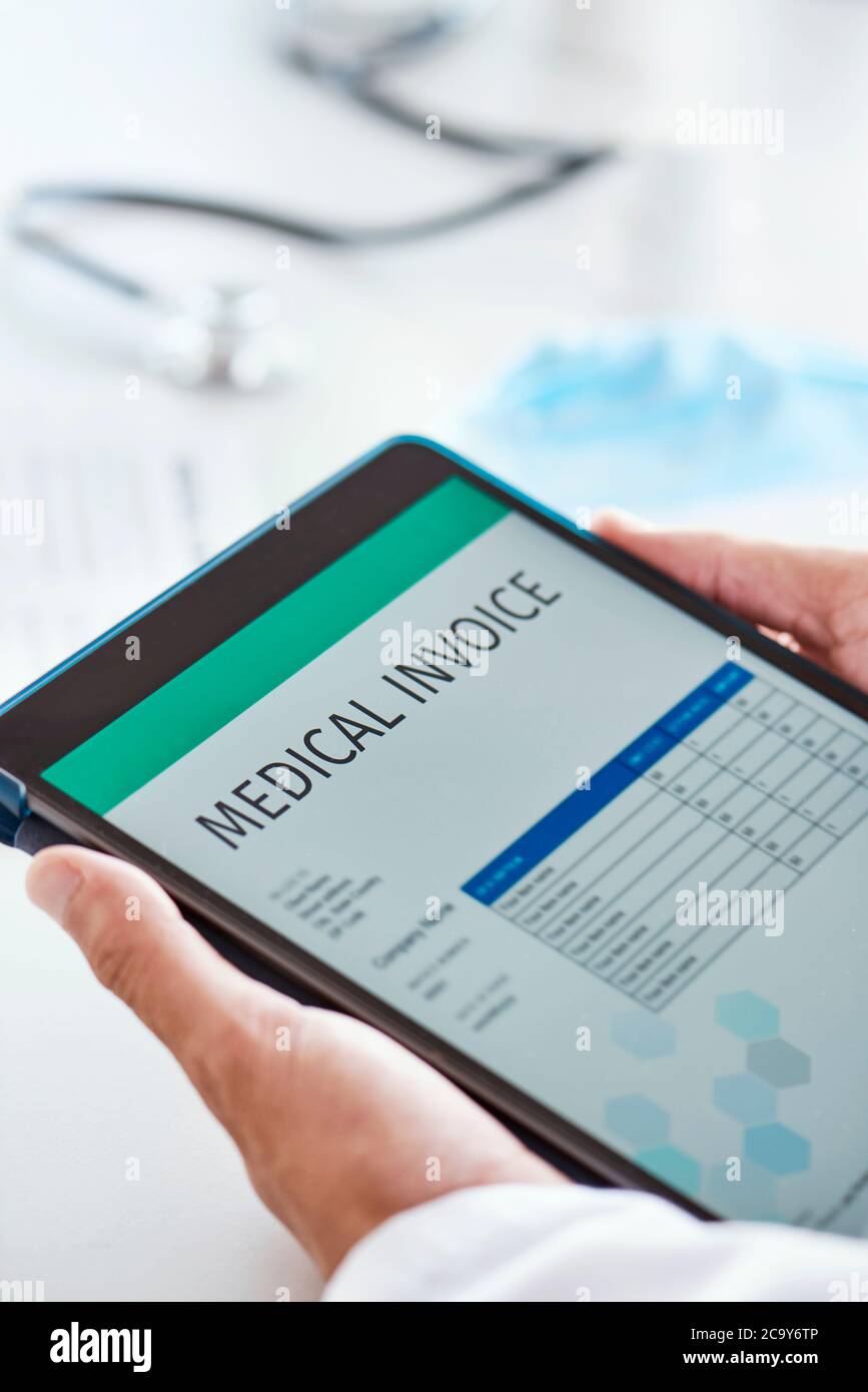 primo piano di un medico caucasico, alla sua scrivania d'ufficio, che controlla una fattura medica in un tablet digitale Foto Stock