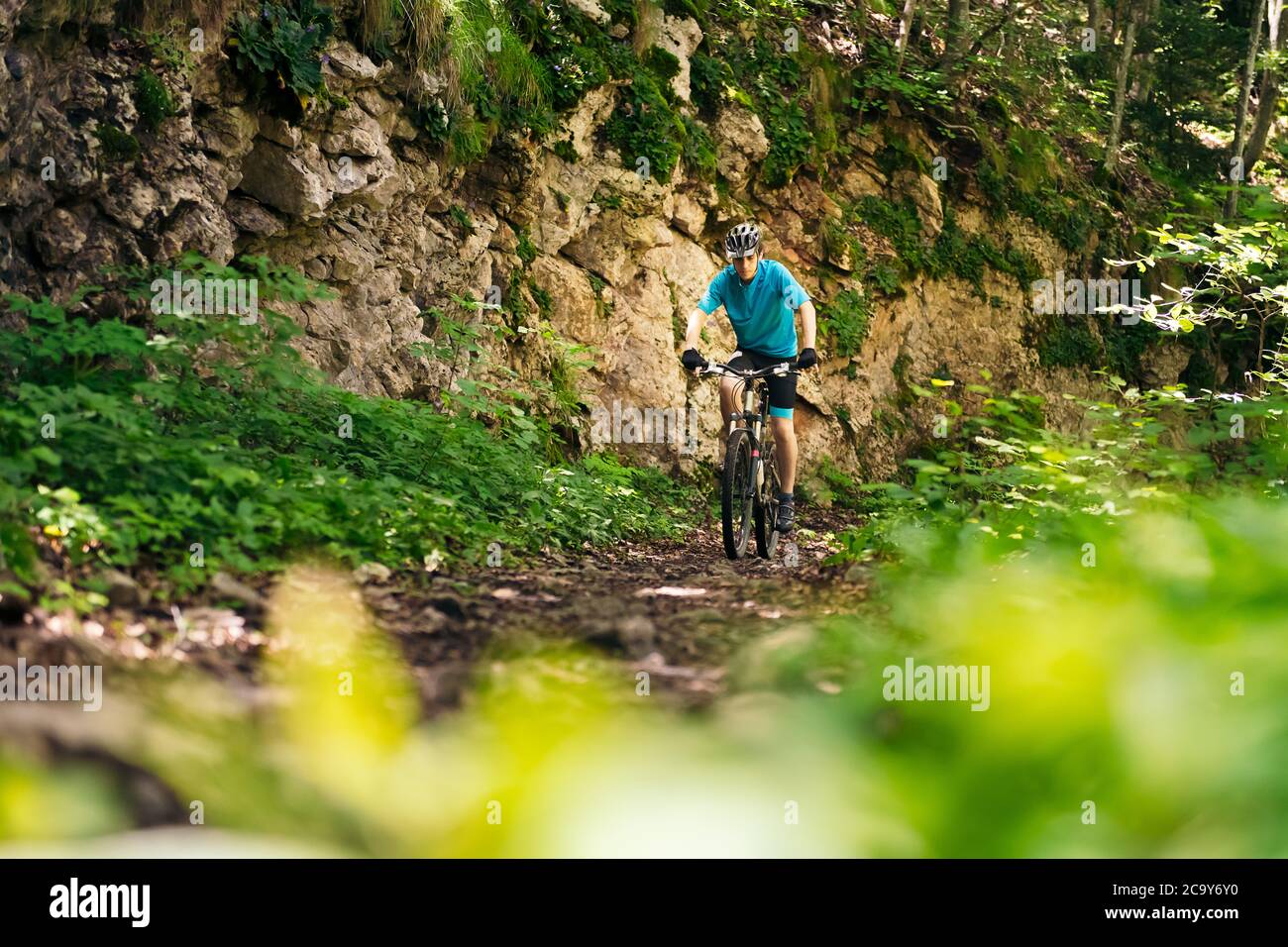 vista frontale di un ciclista che cavalca la sua mountain bike lungo una strada forestale, concetto di sport e stile di vita sano in natura Foto Stock