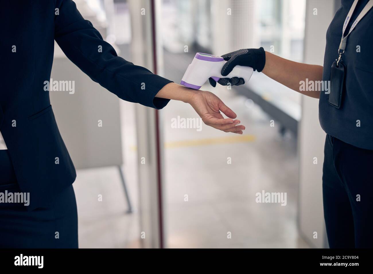 Operaio dell'aeroporto che controlla la temperatura corporea della donna prima del volo Foto Stock