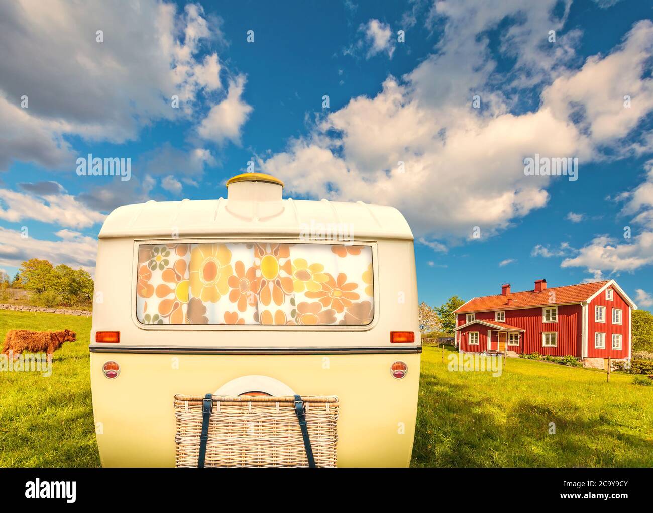 Retro vintage di una carovana in due tonalità di colore giallo e bianco di fronte ad una tipica casa colonica in legno a Smaland, Svezia Foto Stock