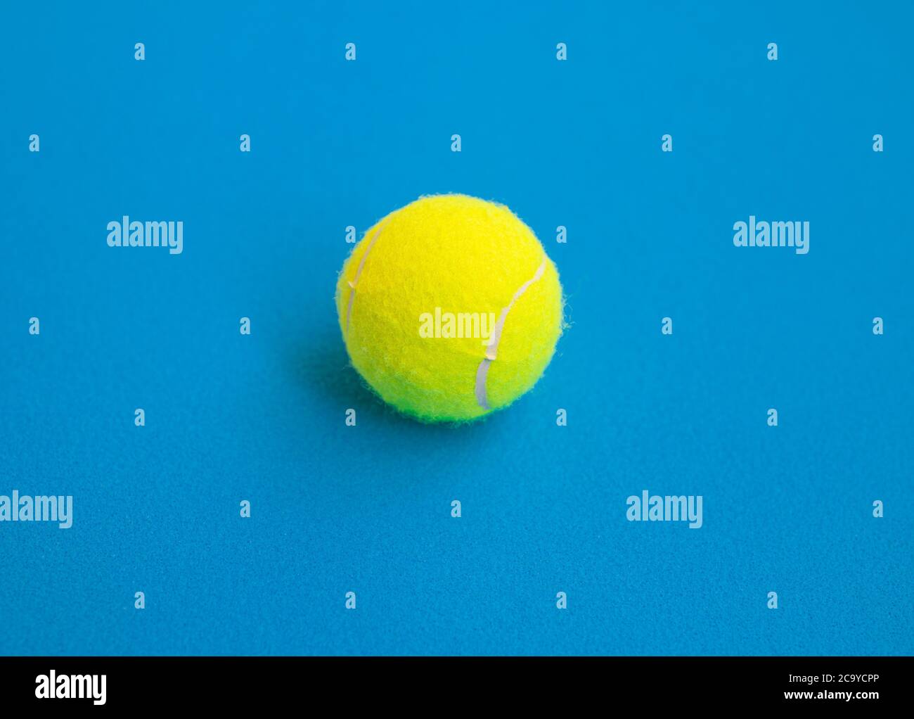 Una palla da tennis gialla isolata su sfondo blu Foto Stock