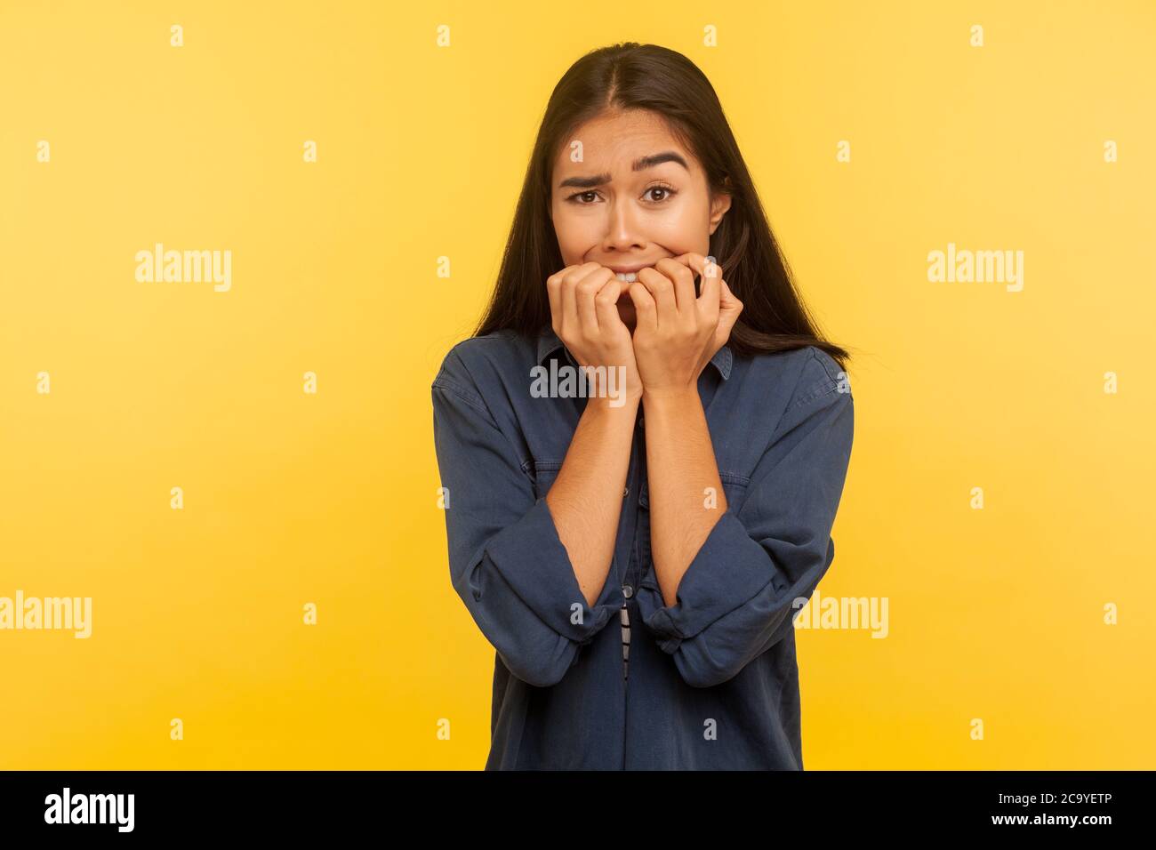 Stress e disturbi d'ansia. Ritratto di preoccupata ragazza spaventato in camicia di denim che muta i chiodi, sentendosi incerto e spaventato, preoccupato per i problemi. Indoo Foto Stock