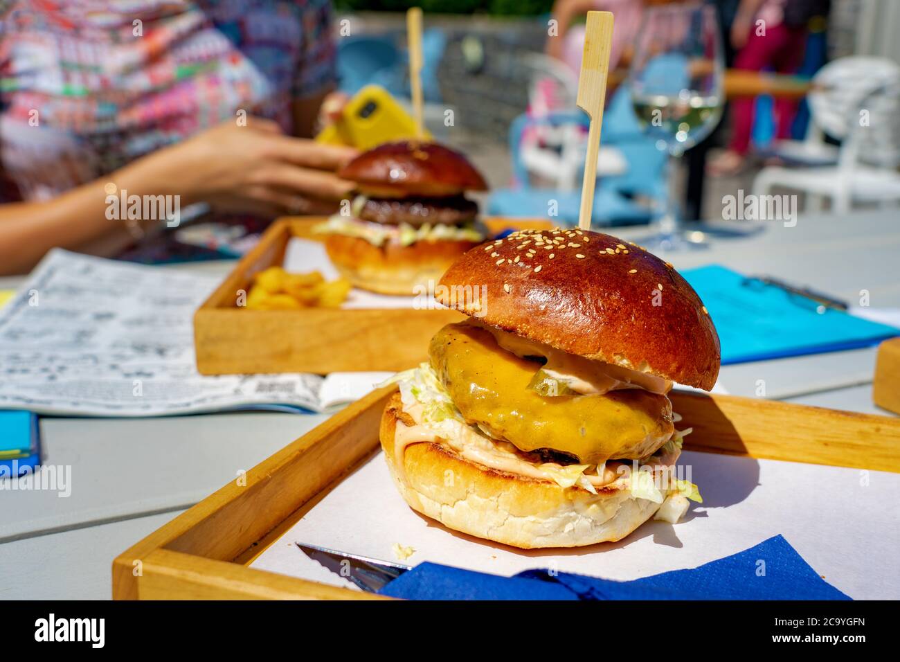 Mangiare hamburger in un evento sociale con gli amici insieme in un ristorante all'aperto su una tavola Foto Stock