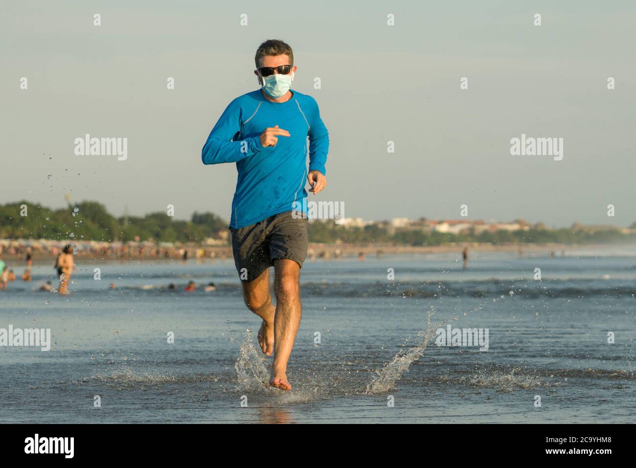 Nuovo allenamento normale di corsa in spiaggia - giovane fit e attraente  uomo jogging a piedi nudi in mare indossando maschera di allenamento dopo  covid19 lockdown sensazione di libero Foto stock - Alamy