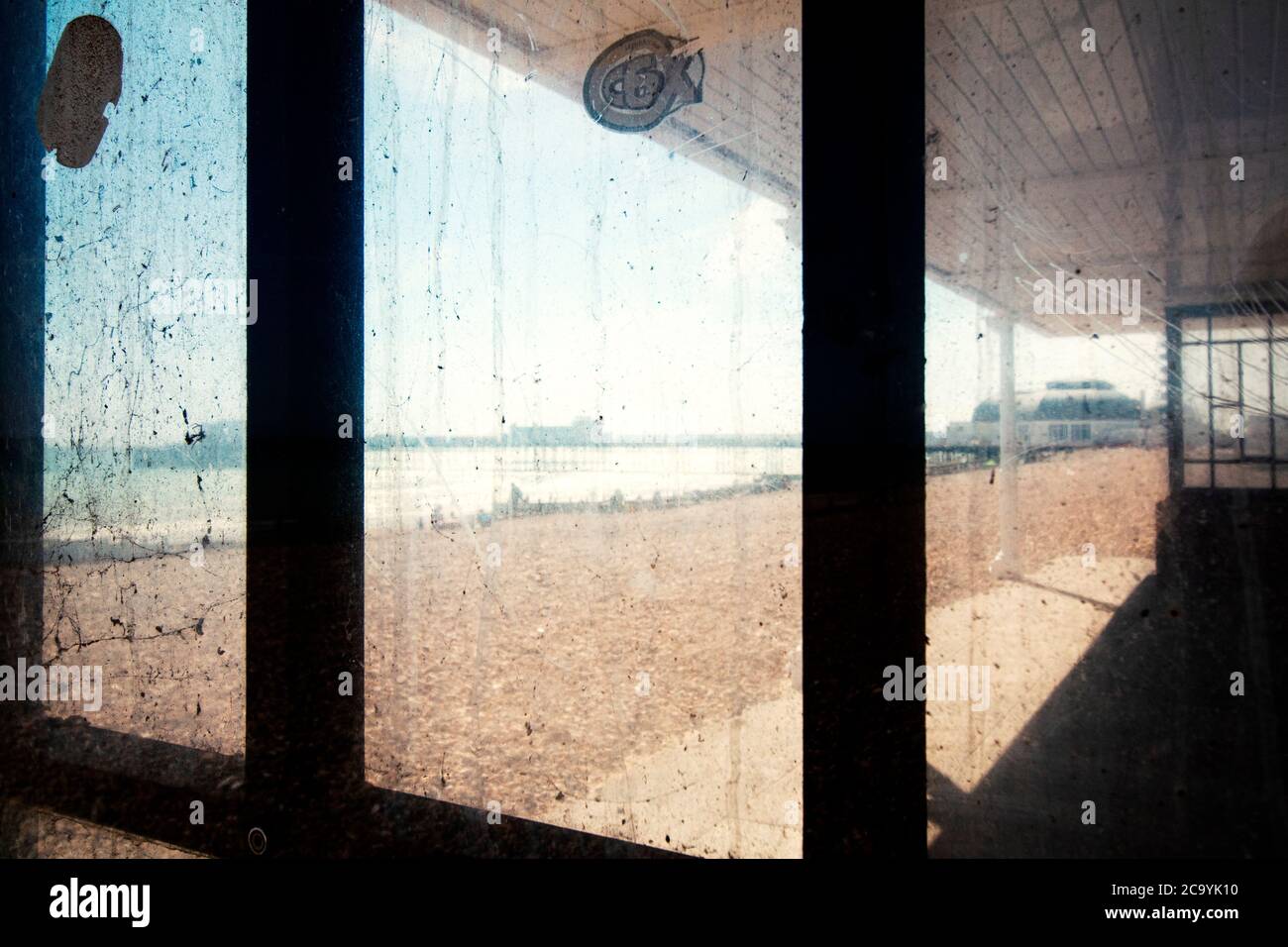 Guardando attraverso una finestra sporca un rifugio sulla spiaggia sul lungomare di Worthing, West Sussex, Regno Unito Foto Stock