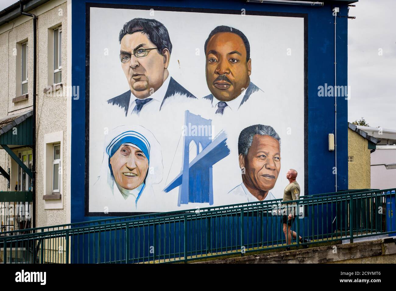 Un uomo cammina attraverso il murale di Bogside a Derry City di John Hume, Martin Luther King Jr, Madre Teresa, e Nelson Mandela. Foto Stock