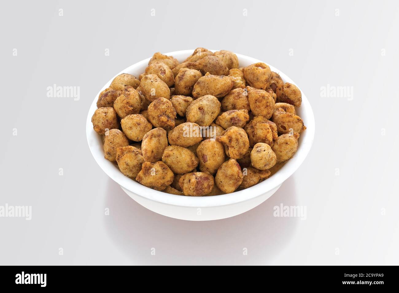 Peanut bhujia, shishing bhujiya, è uno spuntino gujarati molto popolare, ciotola bianca su sfondo bianco, sacchetto che impacchettano snack di strada comune dall'India, selectiv Foto Stock