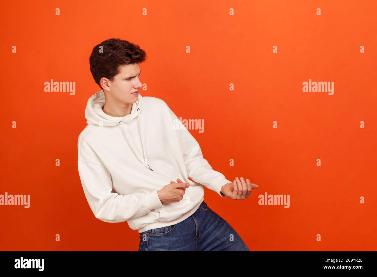 Forte persistente giovane uomo in stile casual felpa con cappuccio tirare qualcosa, intenzionale adolescente raggiungimento di obiettivi, start-up. Riprese in studio al coperto Foto Stock