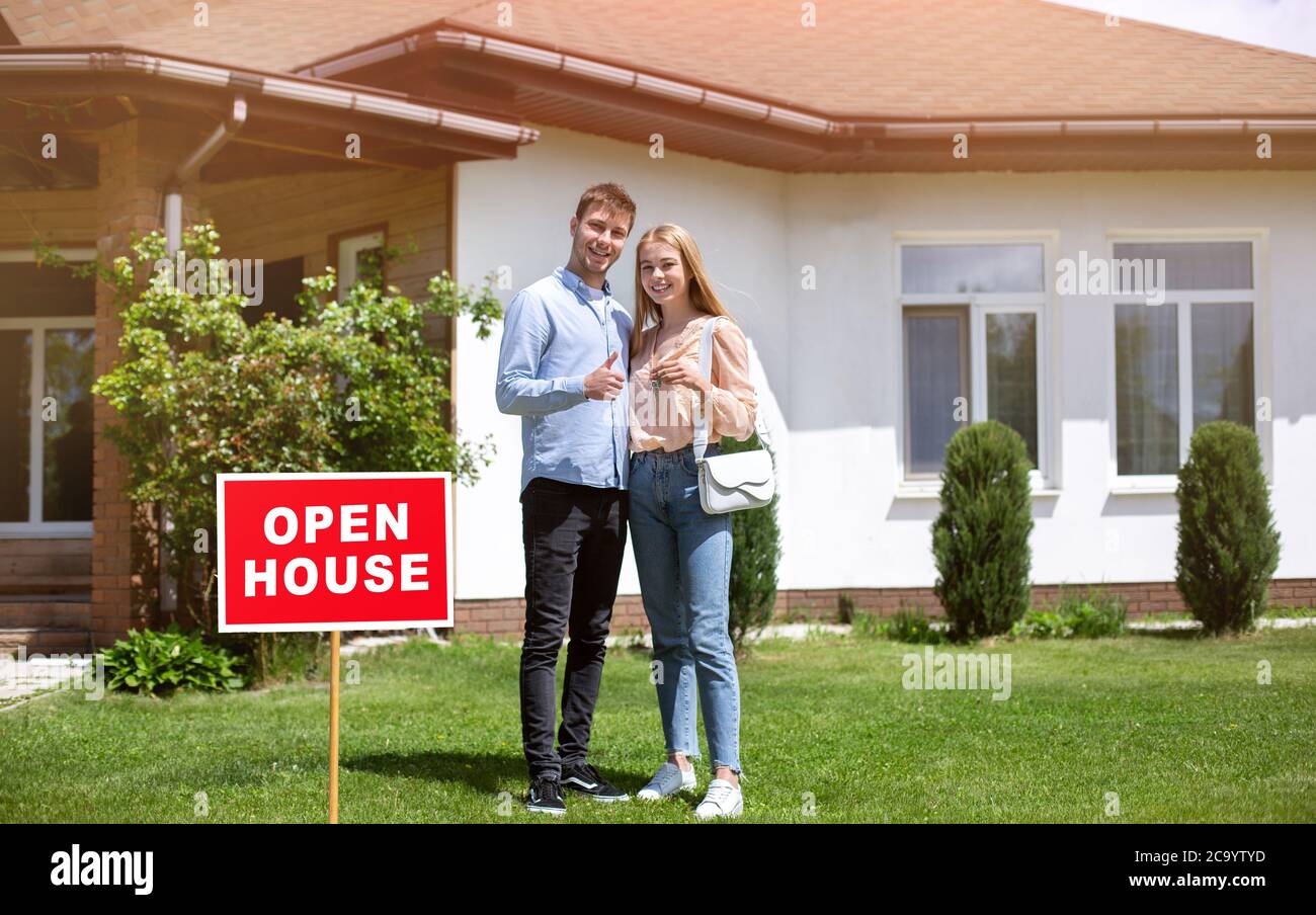Felici proprietari di casa con la chiave di casa di fronte alla loro nuova proprietà, spazio vuoto Foto Stock