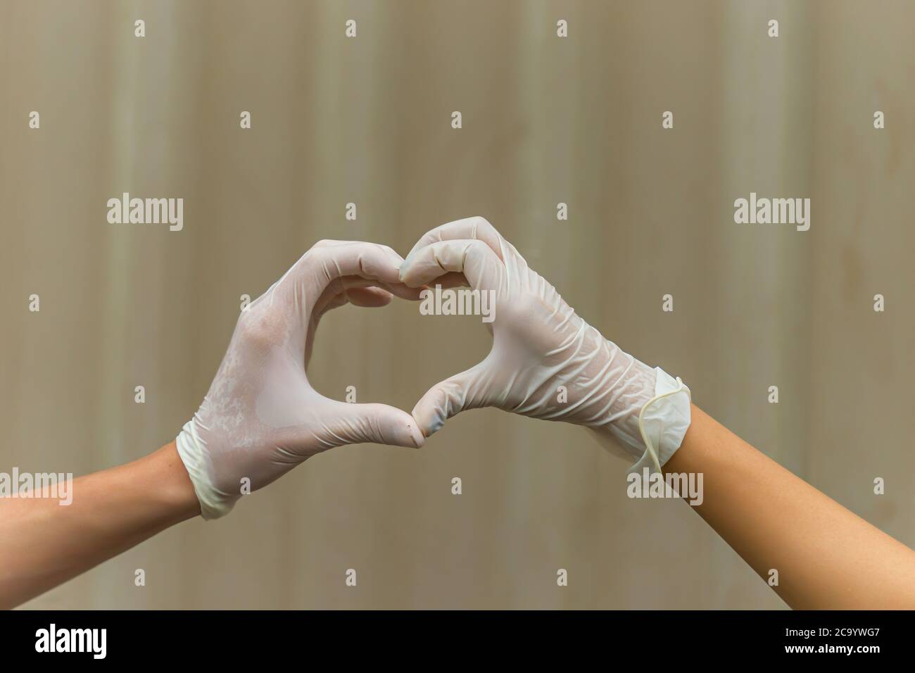 Le mani che si alzano fanno la forma del cuore del dito indossando guanto medico bianco, guanto di gomma per la sicurezza medica professionale e la protezione igienica Coron Foto Stock