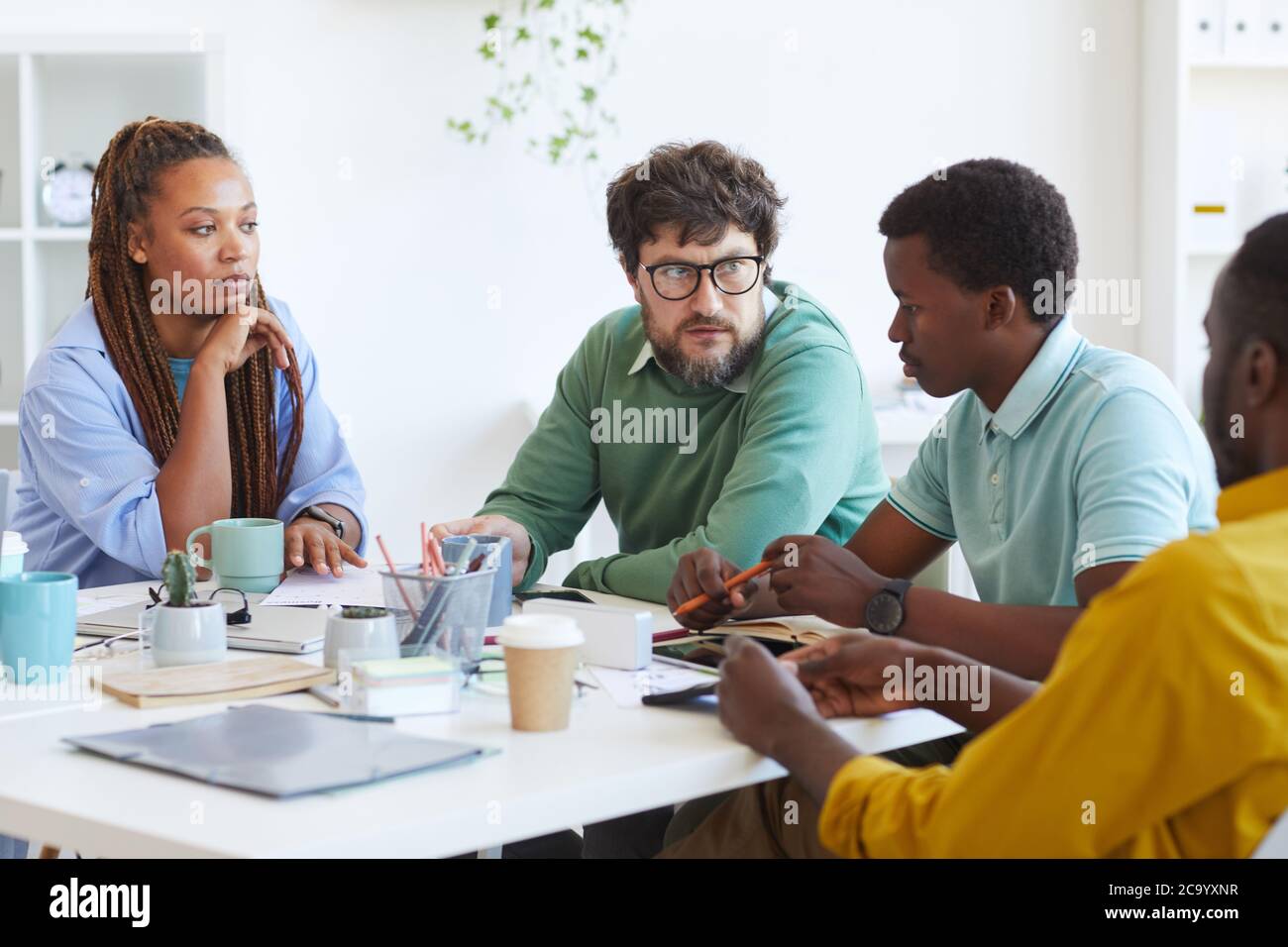Ritratto di manager maturo bearded che parla con il team aziendale multietnico mentre discute i piani durante la riunione in ufficio, copy space Foto Stock