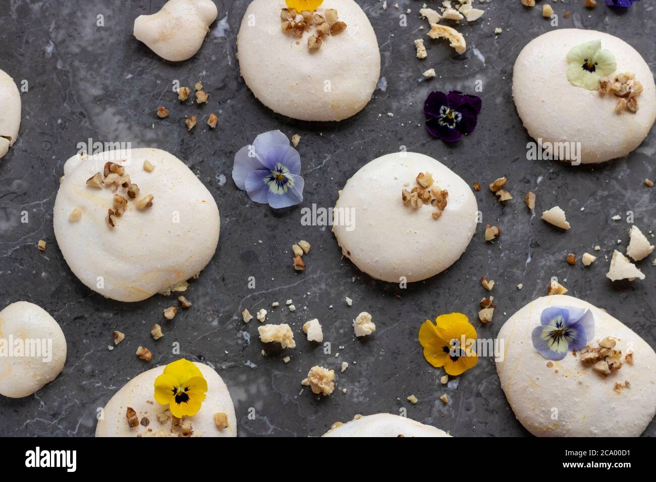 Aquafaba Meringhe ricoperte di fiori commestibili, noci tritate, more e lamponi Foto Stock