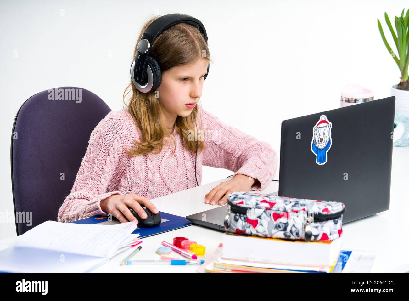 Teenage, ragazza bionda nel maglione rosa è confuso mentre fa le sue lezioni. Homeschooling durante l'isolamento a casa. Foto Stock