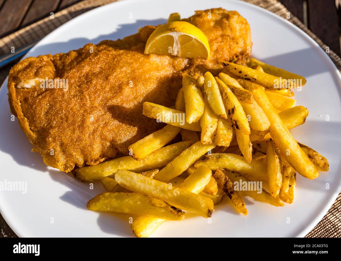 Pesce e patatine di eglefino o cena a base di pesce sul piatto al sole estivo con limone, Scozia, Regno Unito Foto Stock