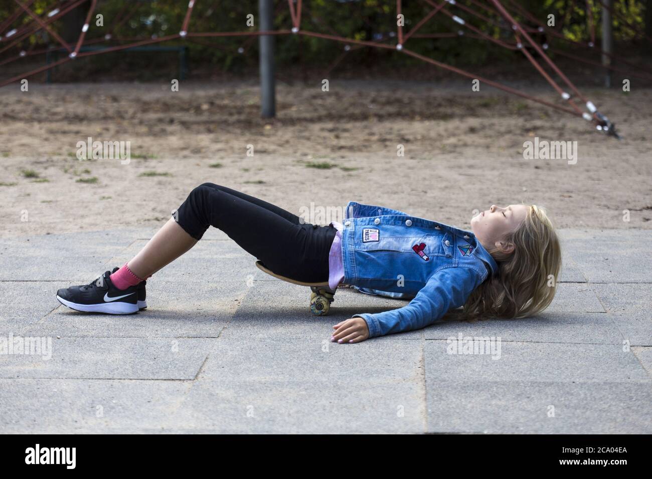 Ragazza (10) giace su skateboard, Kiel, Schleswig-Holstein, Germania Foto Stock