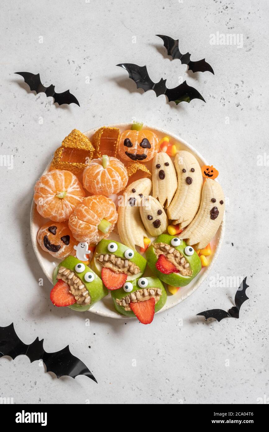 Delizie salutari di Halloween. Fantasmi di banana, zucche arancioni di clementine e montaggi di mostro di Apple Foto Stock