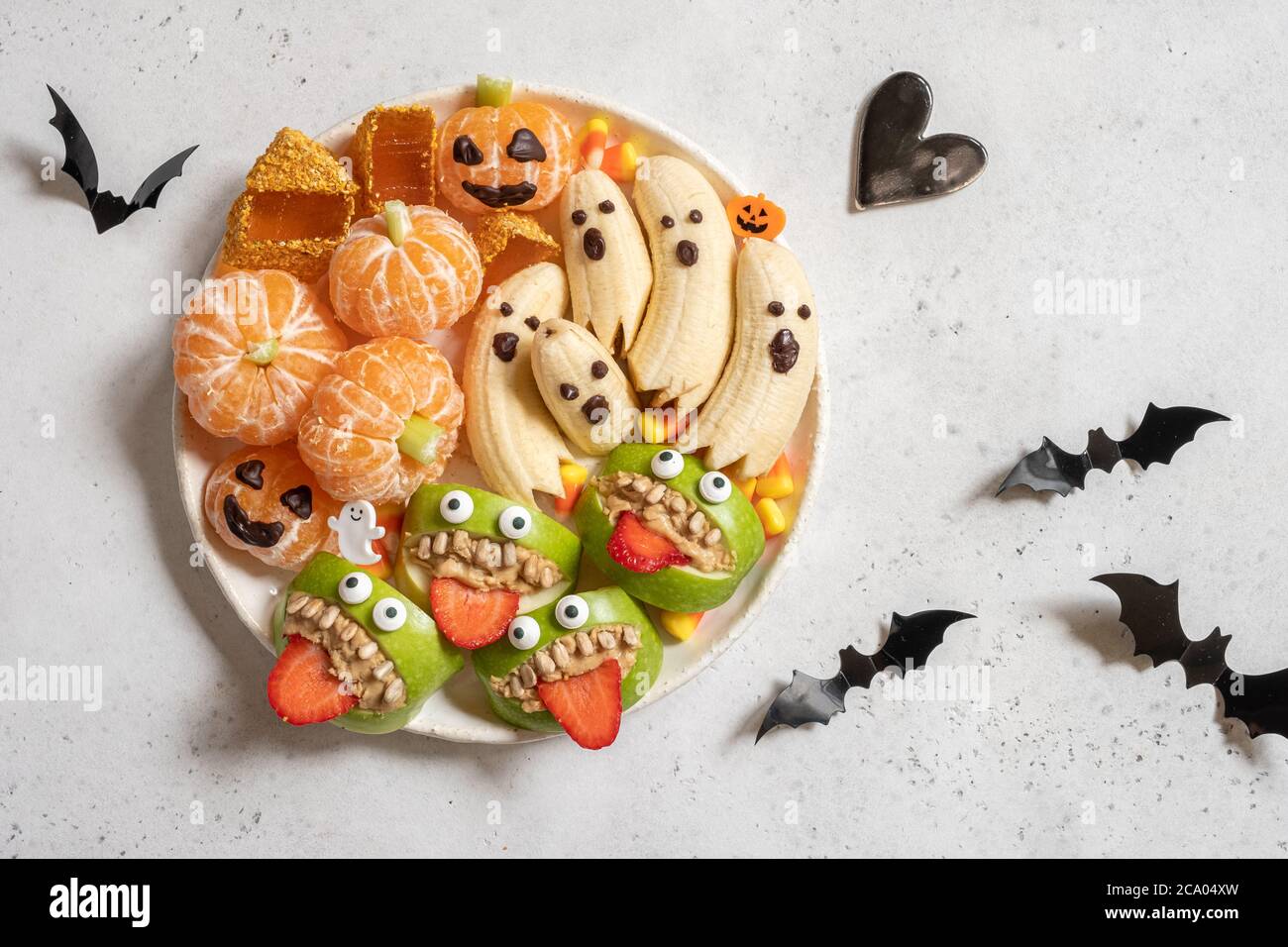 Delizie salutari di Halloween. Fantasmi di banana, zucche arancioni di clementine e montaggi di mostro di Apple Foto Stock