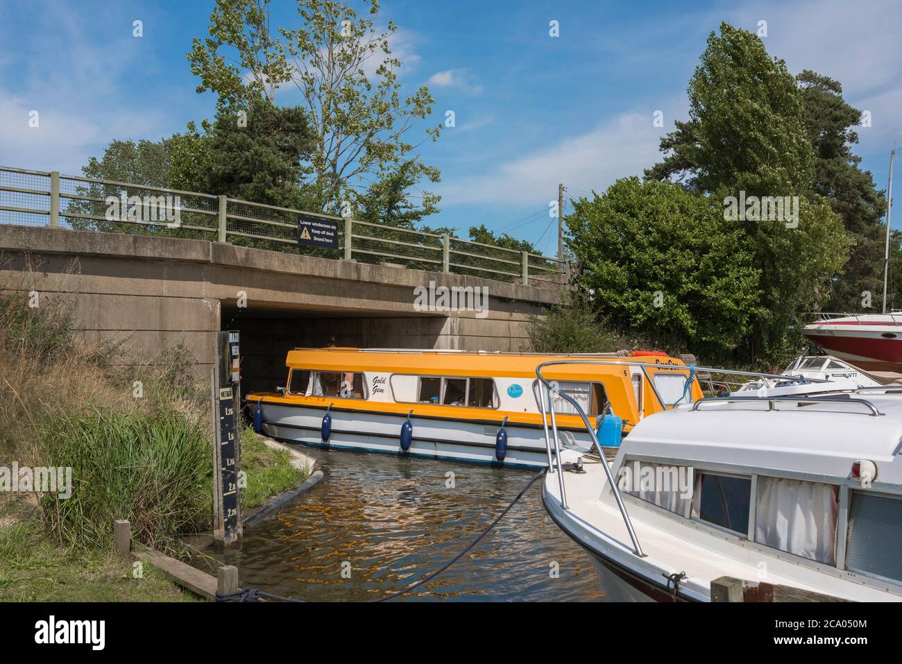 Ludham Bridge, vista in estate di una barca da diporto che naviga sotto il ponte Ludham nel centro dei Norfolk Broads, East Anglia, Inghilterra, Regno Unito Foto Stock