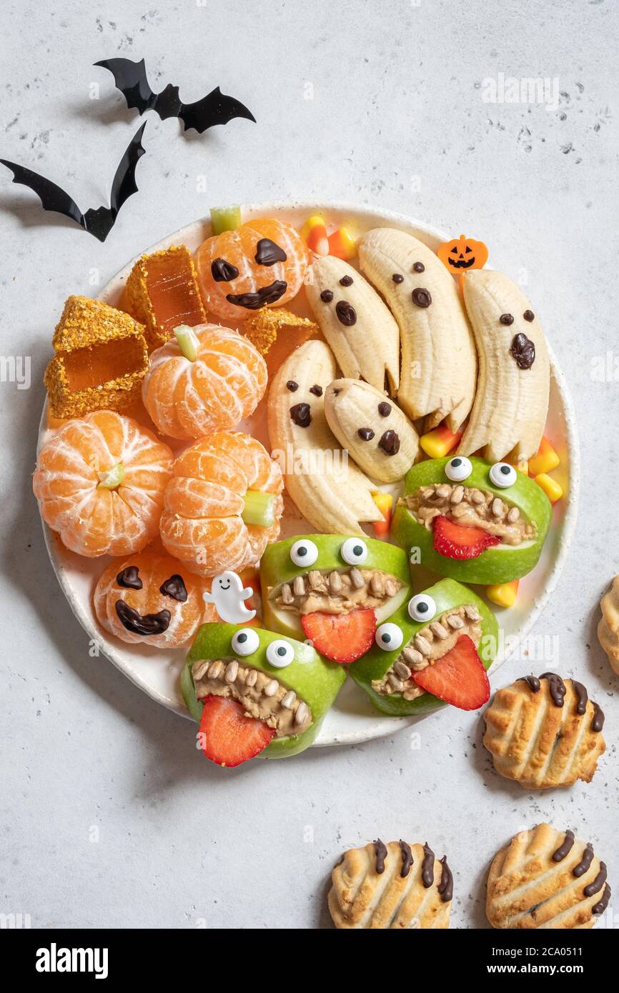 Delizie salutari di Halloween. Fantasmi di banana, zucche arancioni di clementine e montaggi di mostro di Apple Foto Stock