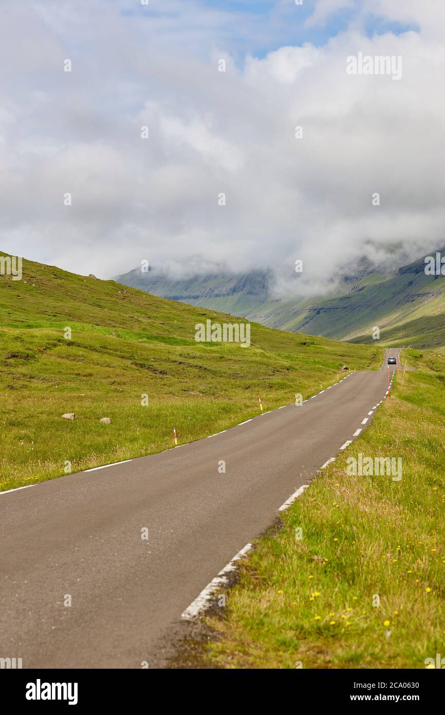 Le isole Faroe pittoresca strada circondata da verde fiordo paesaggio. Danimarca Foto Stock