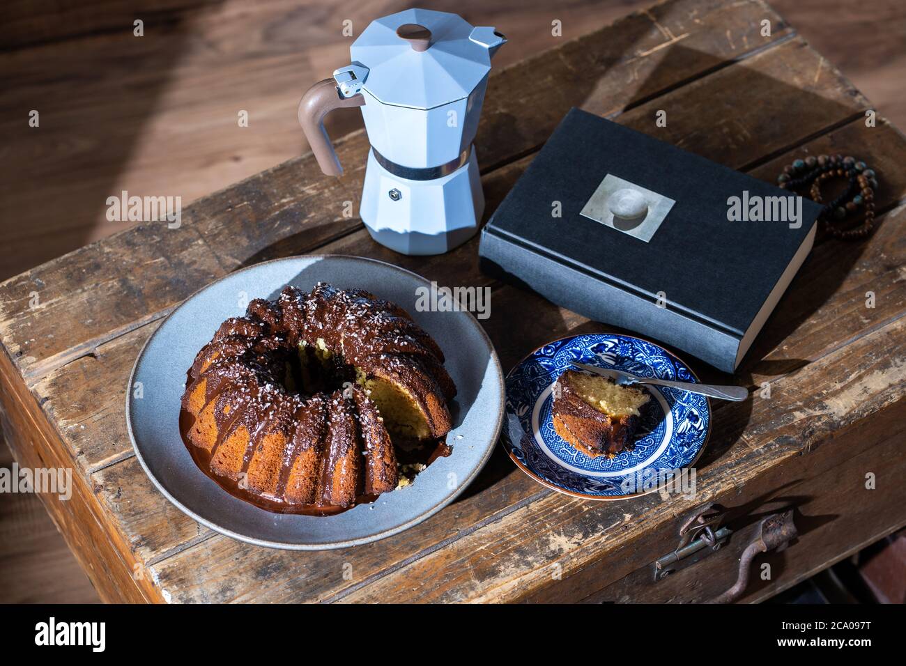 Torta di Pasqua, buon libro e caffè caldo su vecchio tavolo di legno scuro - bel pomeriggio durante il soggiorno a casa. Foto Stock