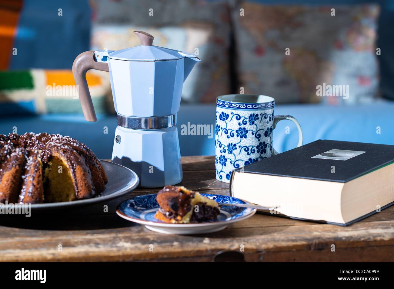 Deliziosa fetta di torta di Pasqua, buon libro e caffè caldo su vecchio tavolo di legno scuro - perfetto mattina facile durante il soggiorno a casa. Foto Stock
